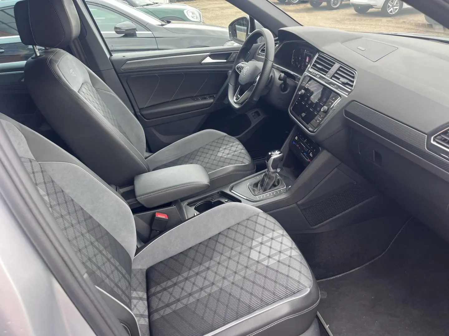 Vue intérieure côté conducteur du Volkswagen Tiguan 1.4 eHybrid 2023 avec sièges sport gris et tableau de bord moderne.