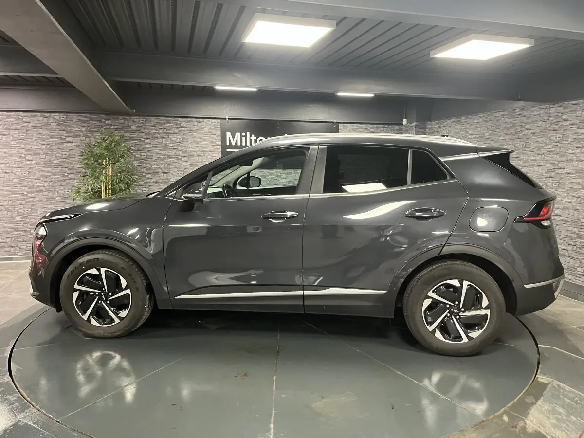 Vue latérale droite du KIA SPORTAGE gris métallisé 2022 avec jantes alliage 17 pouces et poignées chromées.