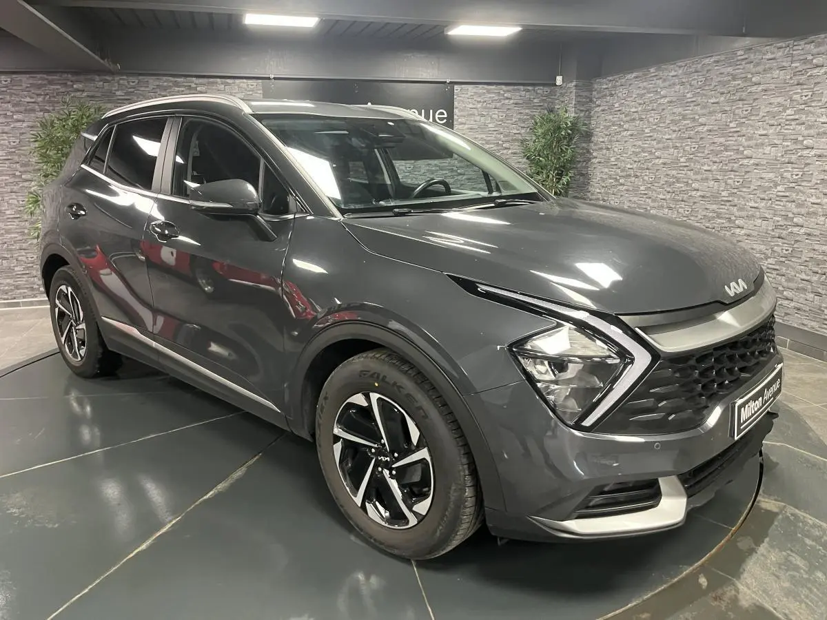 KIA SPORTAGE gris métallisé en 3/4 avant droit avec calandre noire laquée et jantes alliage 17 pouces.