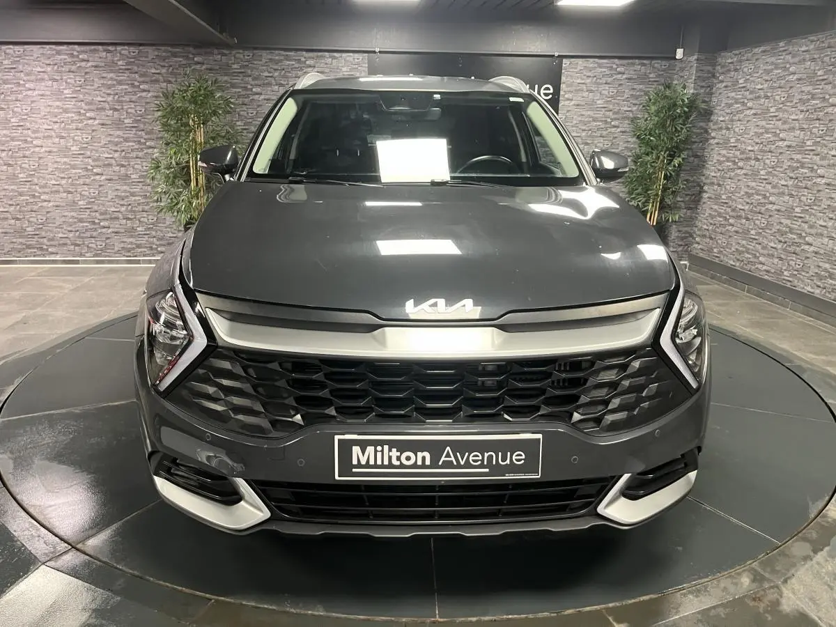 Vue frontale d'un KIA SPORTAGE gris métallisé 2022 avec calandre noire laquée et inserts chromés.