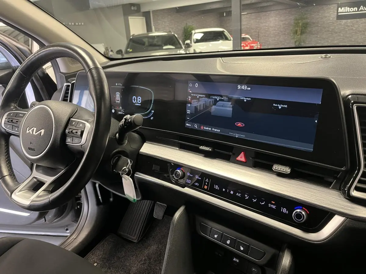 Vue intérieure du tableau de bord du Kia Sportage 2022 avec écran tactile large et volant cuir noir.