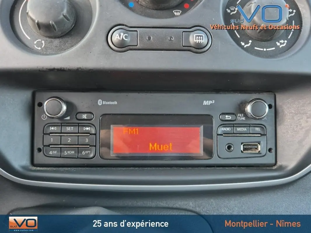 Tableau de bord du Renault Kangoo blanc 2016 montrant la radio Bluetooth et commandes climatisation manuelle.