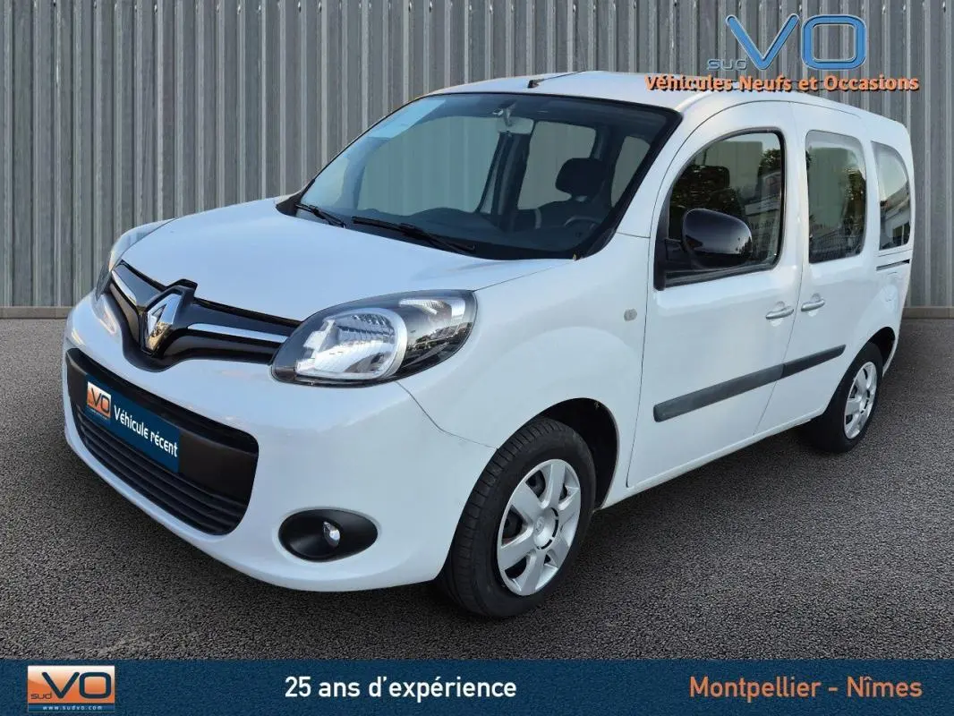 Renault Kangoo blanc en 3/4 avant droit, avec porte latérale et vitres surteintées visibles.