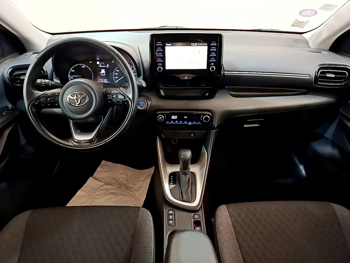 Intérieur de Toyota Yaris hybride 2021, vue frontale du tableau de bord avec écran tactile et volant multifonctions cuir.
