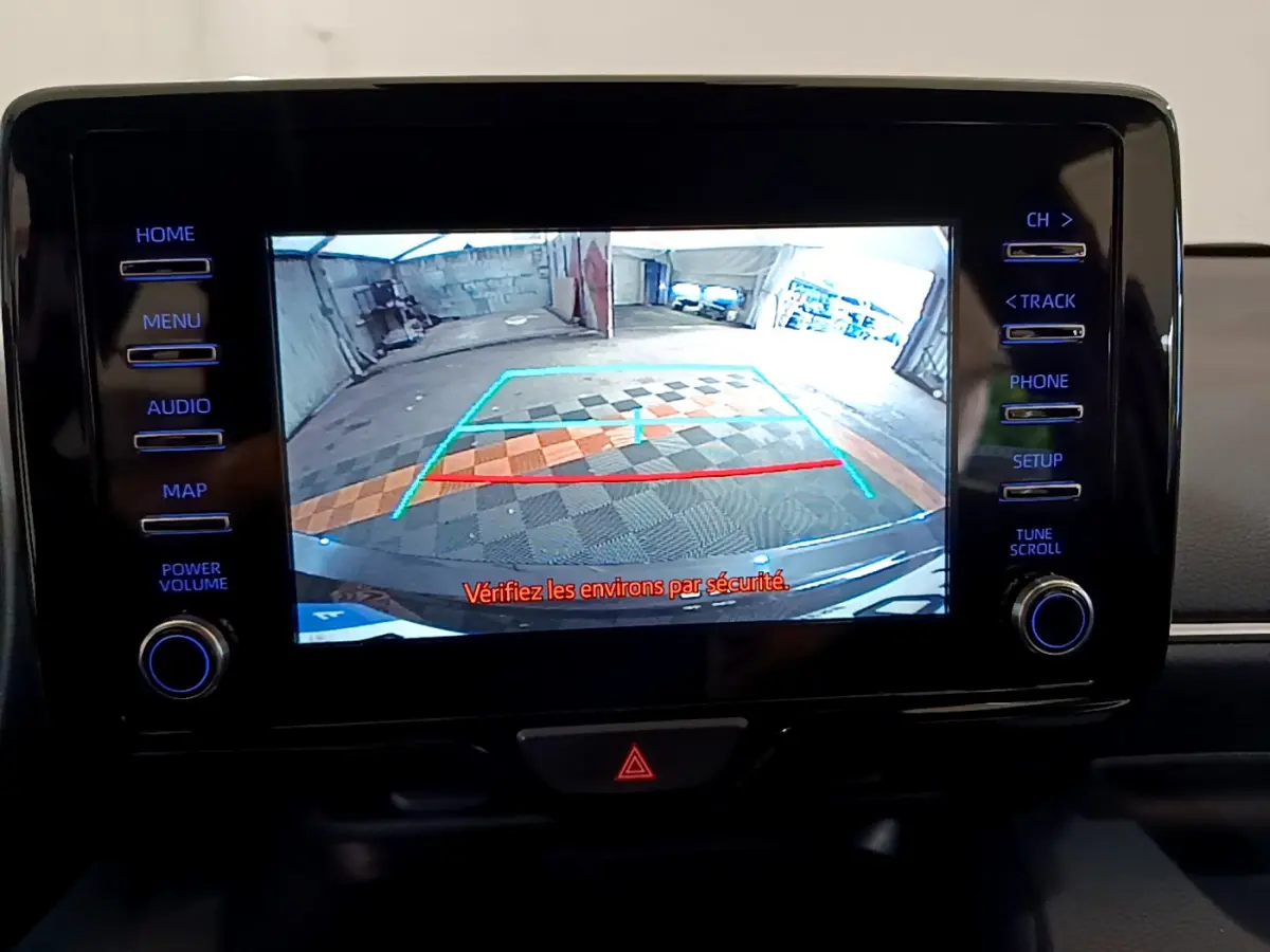 Écran tactile central affichant la caméra de recul de la Toyota Yaris hybride gris clair, avec lignes de guidage colorées.