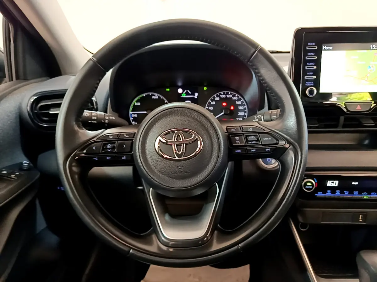 Vue intérieure centrée sur le volant cuir multifonctions d'une Toyota Yaris hybride 2021 avec écran tactile et tableau de bord numérique.
