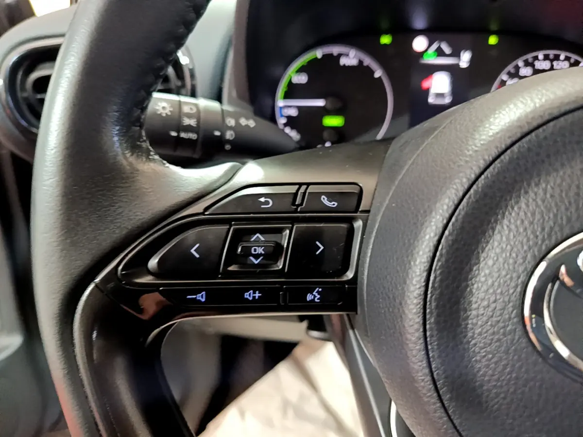 Gros plan sur le volant cuir de la Toyota Yaris hybride 2021, côté gauche avec commandes multifonctions visibles.