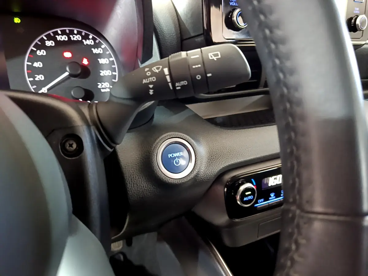 Détail intérieur montrant le bouton Power bleu et le combiné d'instruments de la Toyota Yaris hybride 2021.
