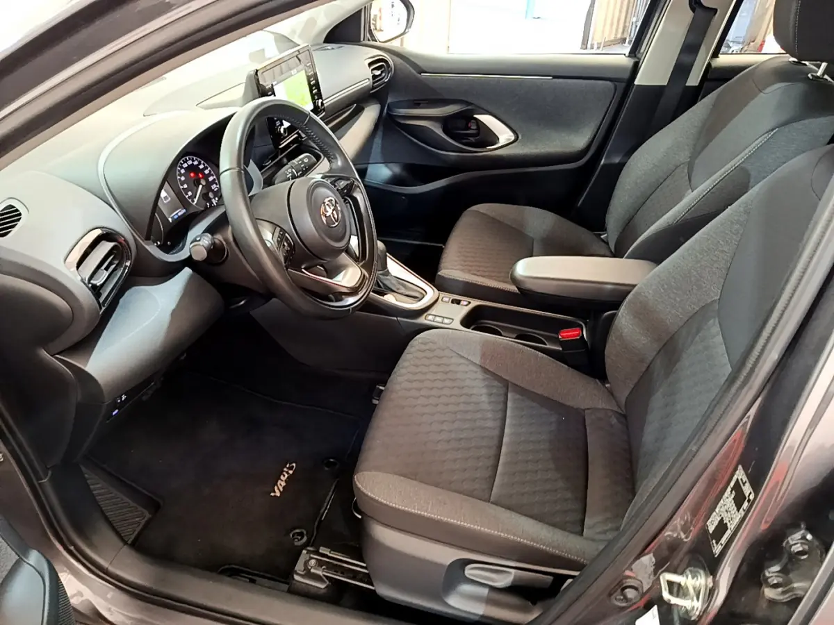 Intérieur avant droit d'une Toyota Yaris hybride 2021, sièges gris, volant cuir multifonctions et écran tactile central.