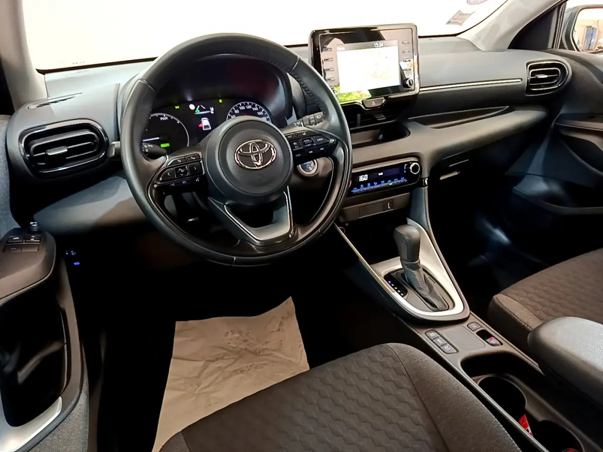 Vue intérieure de la Toyota Yaris hybride 2021, tableau de bord et volant cuir noir avec écran tactile central.