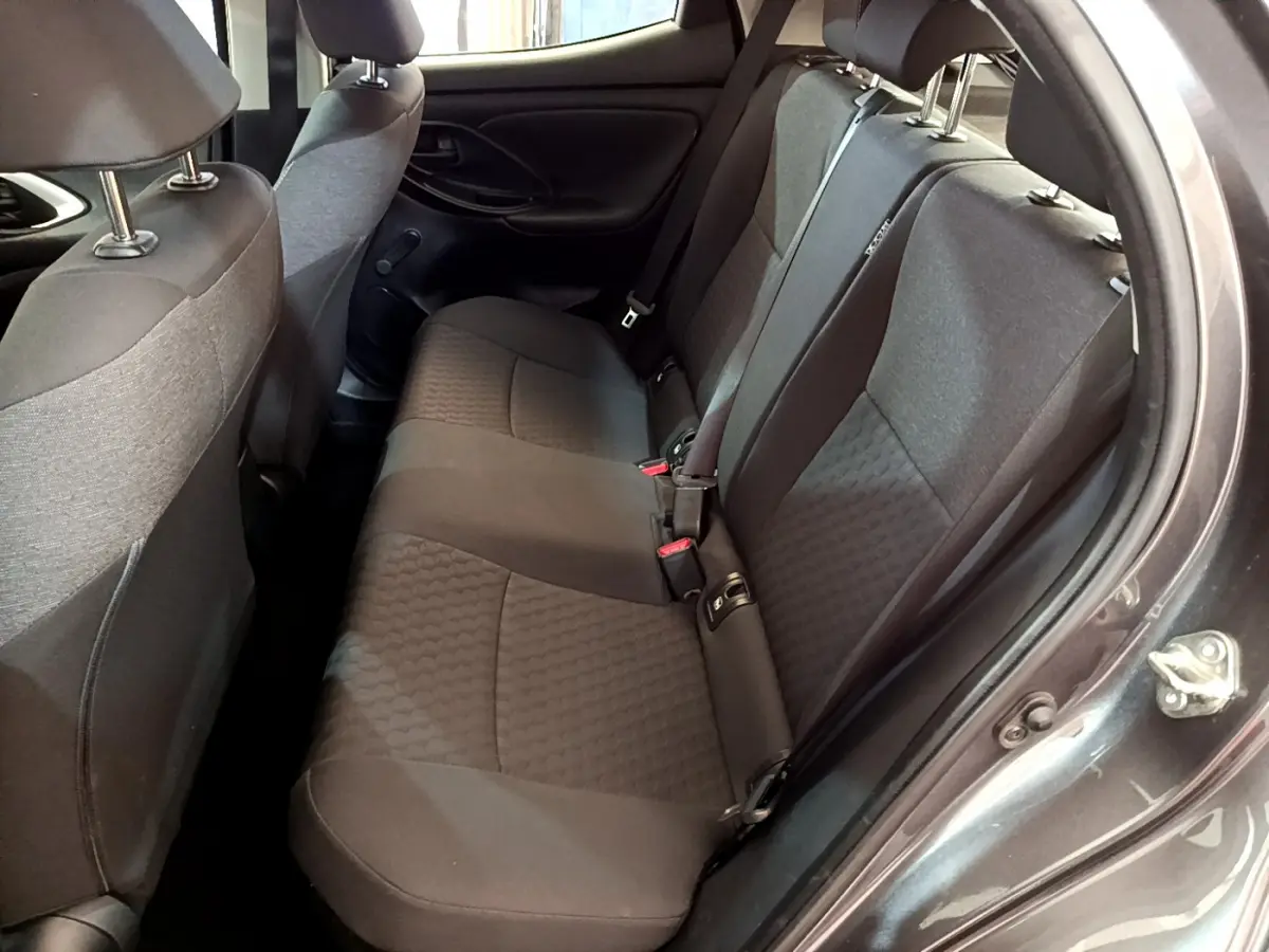 Vue intérieure côté droit sur la banquette arrière grise foncée de la Toyota Yaris hybride 2021 avec ceintures et appuie-têtes visibles