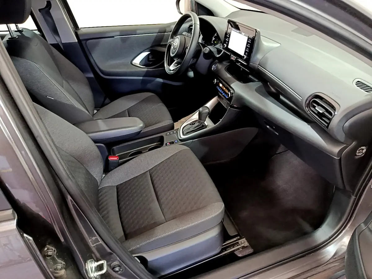 Intérieur avant droit de la Toyota Yaris hybride 2021 gris clair, avec tableau de bord tactile et sièges tissu noirs.