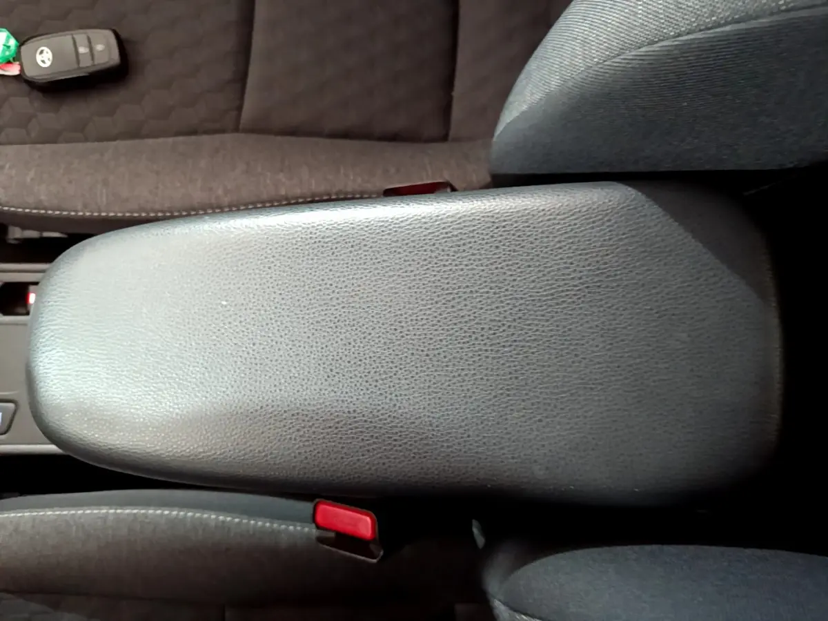 Vue plongeante sur l'accoudoir central en cuir gris et la clé Toyota posée sur le siège tissu foncé d'une Yaris hybride 2021.