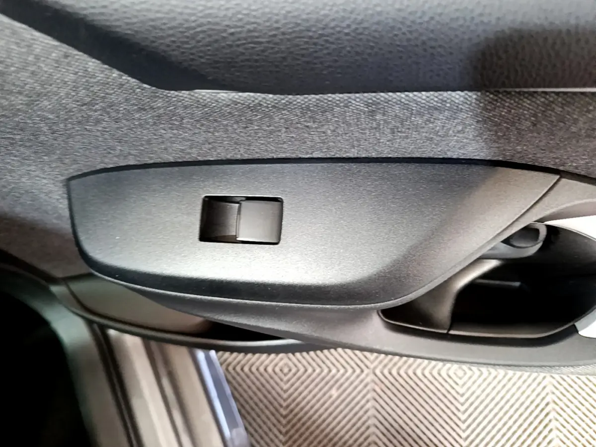 Détail de la commande de vitre côté conducteur dans l’habitacle gris clair de la Toyota Yaris hybride 2021.