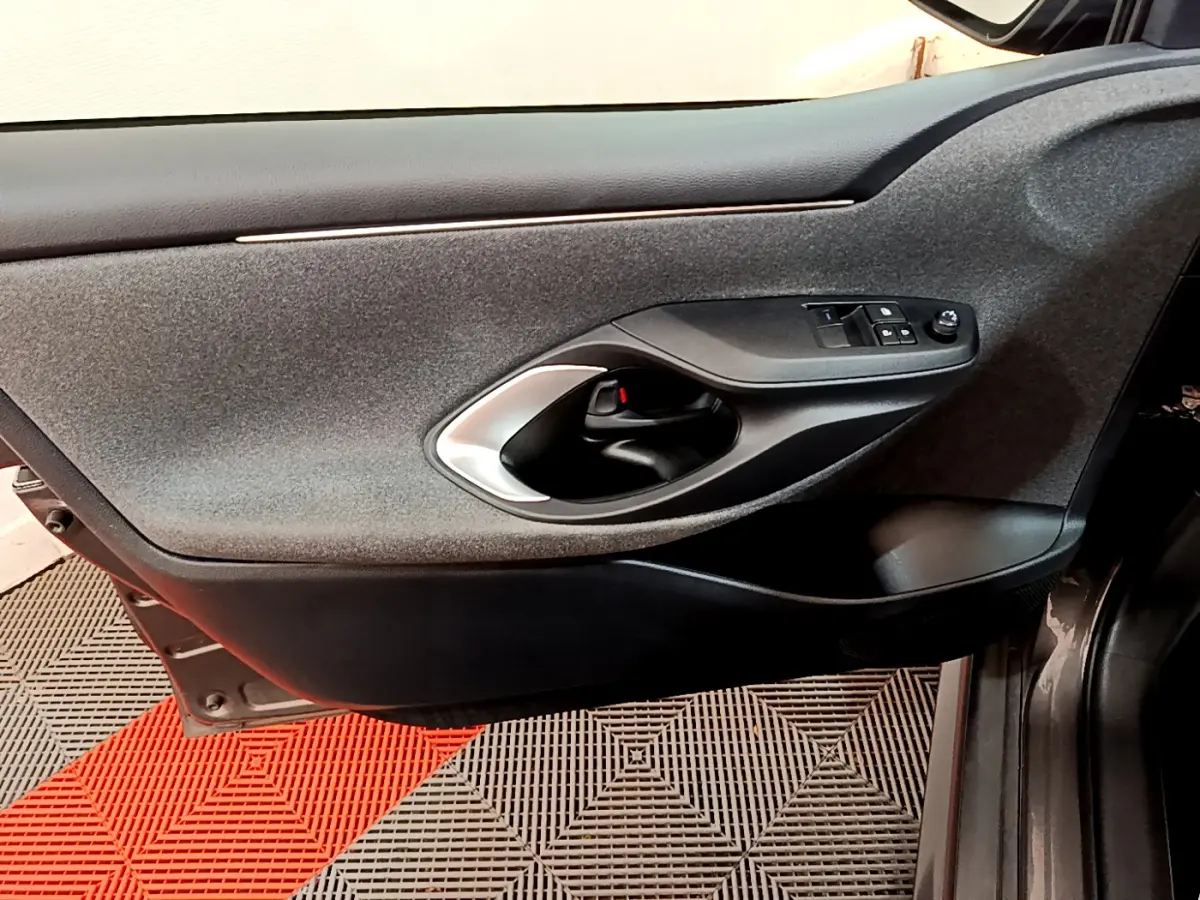 Gros plan sur la porte côté conducteur gris clair de la Toyota Yaris hybride 2021 avec commandes de vitres et poignée intérieure noire.