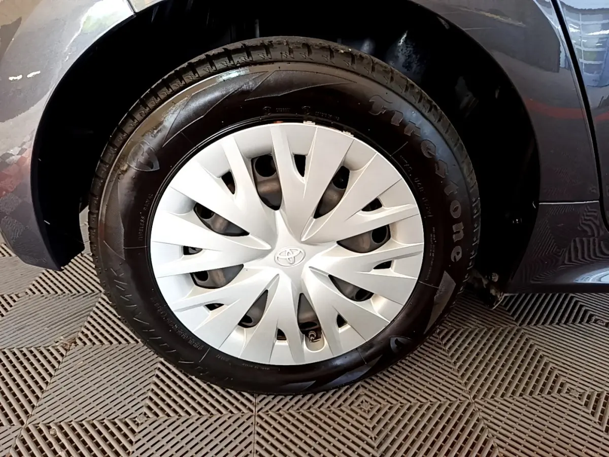 Gros plan sur la roue avant droite gris clair de la Toyota Yaris Hybride 116h avec enjoliveur Toyota distinctif.