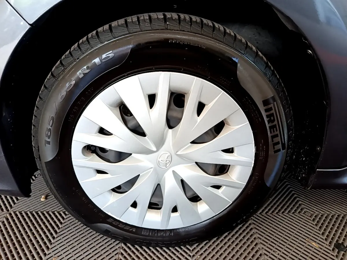 Gros plan sur la roue avant gauche d'une Toyota Yaris hybride gris clair avec enjoliveur blanc et pneu Pirelli.