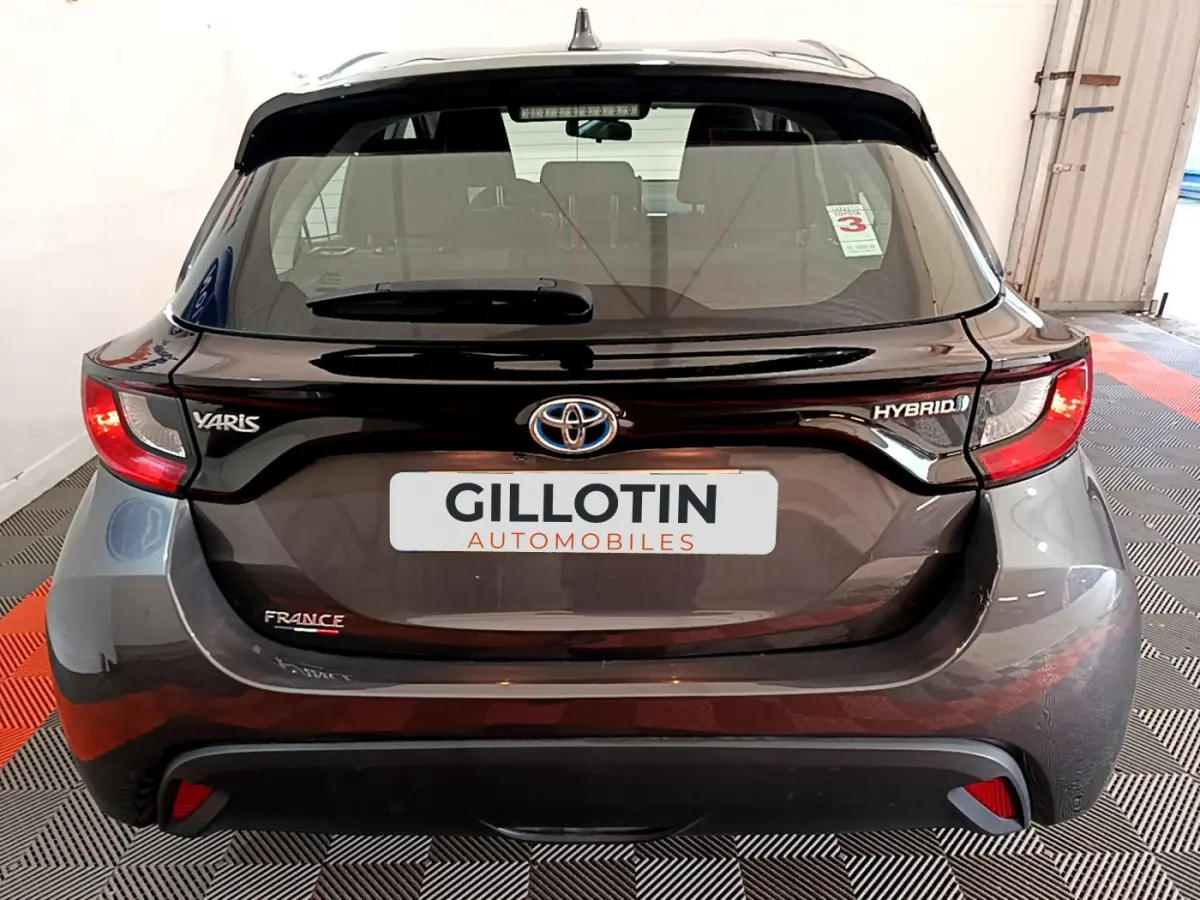 Vue arrière d'une Toyota Yaris hybride gris clair avec badges Yaris, Hybrid et France visibles sur le hayon.