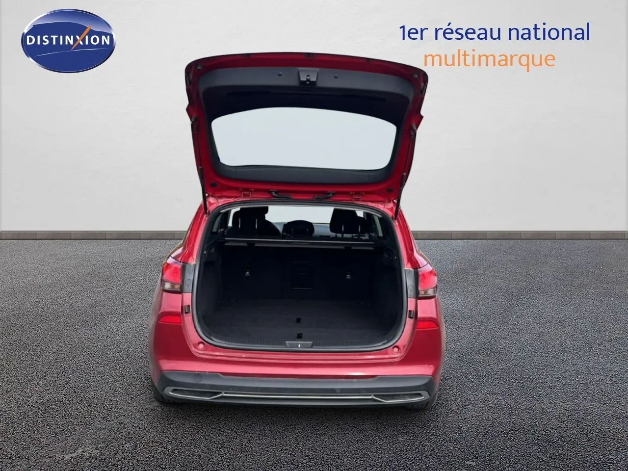 Vue arrière d'une Hyundai i30 SW 2023 en rouge Sunset Red Metal avec coffre ouvert montrant l'espace de chargement.
