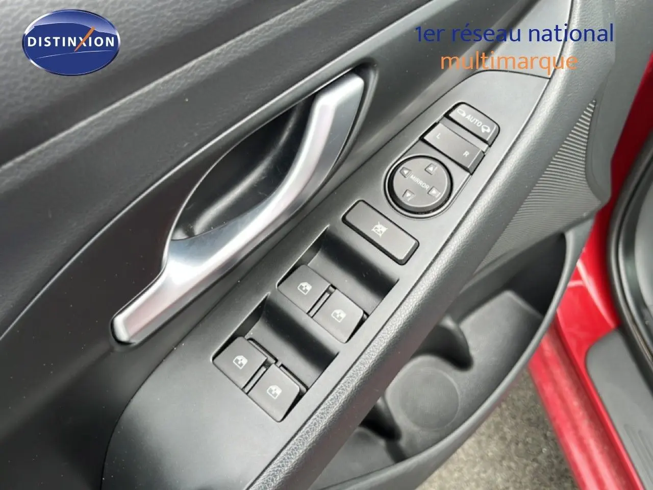 Gros plan sur la commande des vitres et rétroviseurs côté conducteur d'une Hyundai i30 SW rouge Sunset Red 2023.