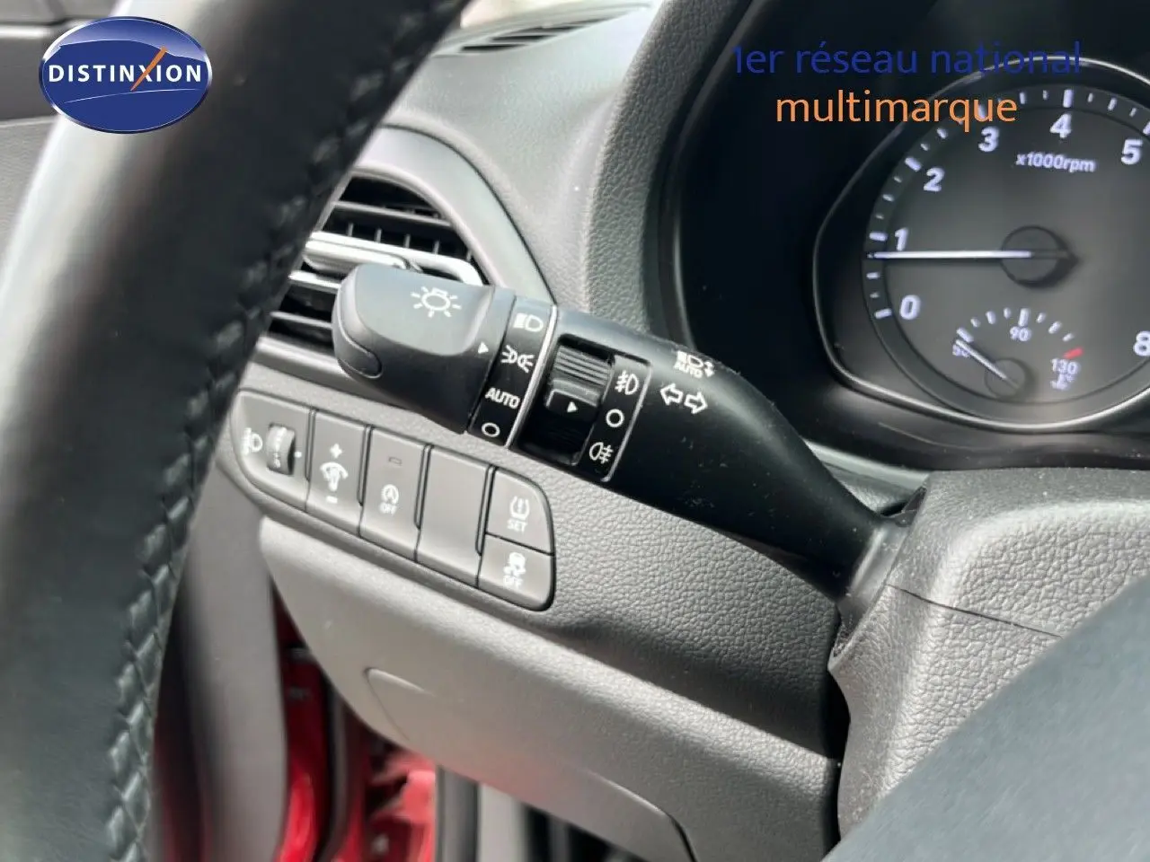 Détail du commodo d'éclairage et tableau de bord partiel côté gauche d'une Hyundai i30 SW rouge Sunset 2023.