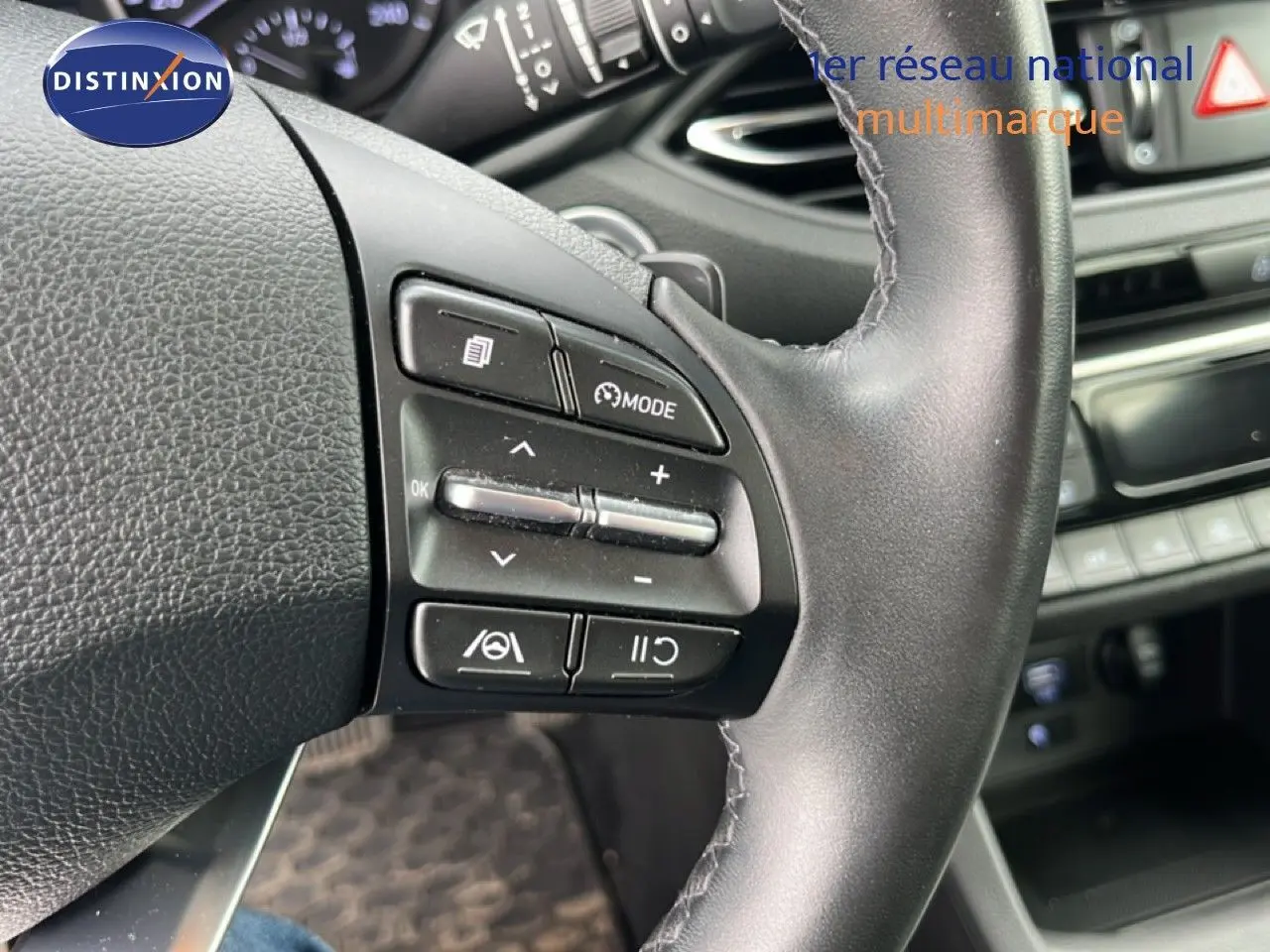 Gros plan sur le volant noir de la Hyundai i30 SW 2023, montrant les commandes intégrées à gauche.