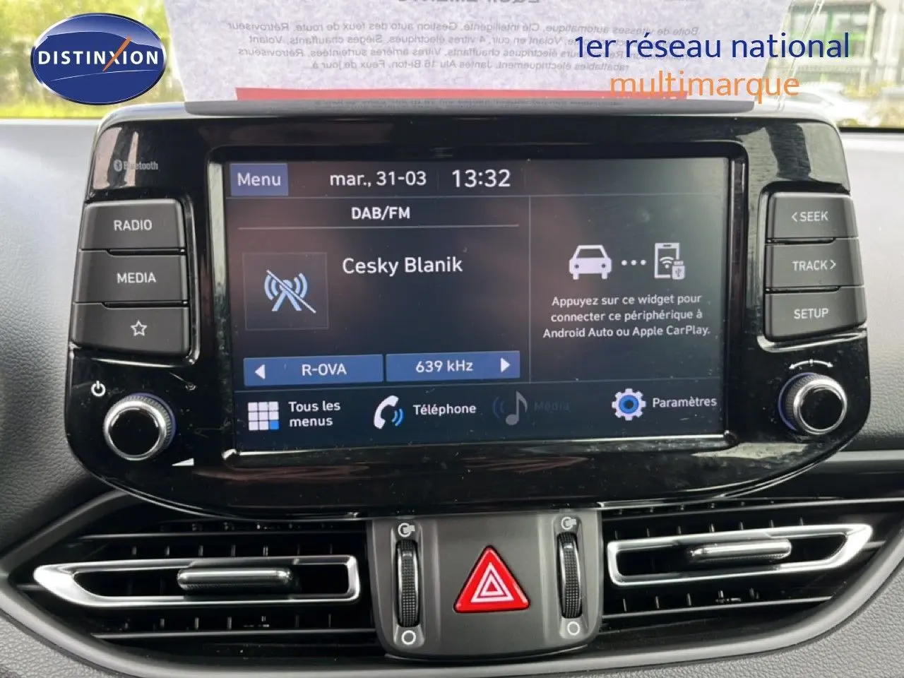Écran tactile central de la Hyundai i30 SW 2023 en Sunset Red, affichant la radio DAB/FM et les commandes multimédia.