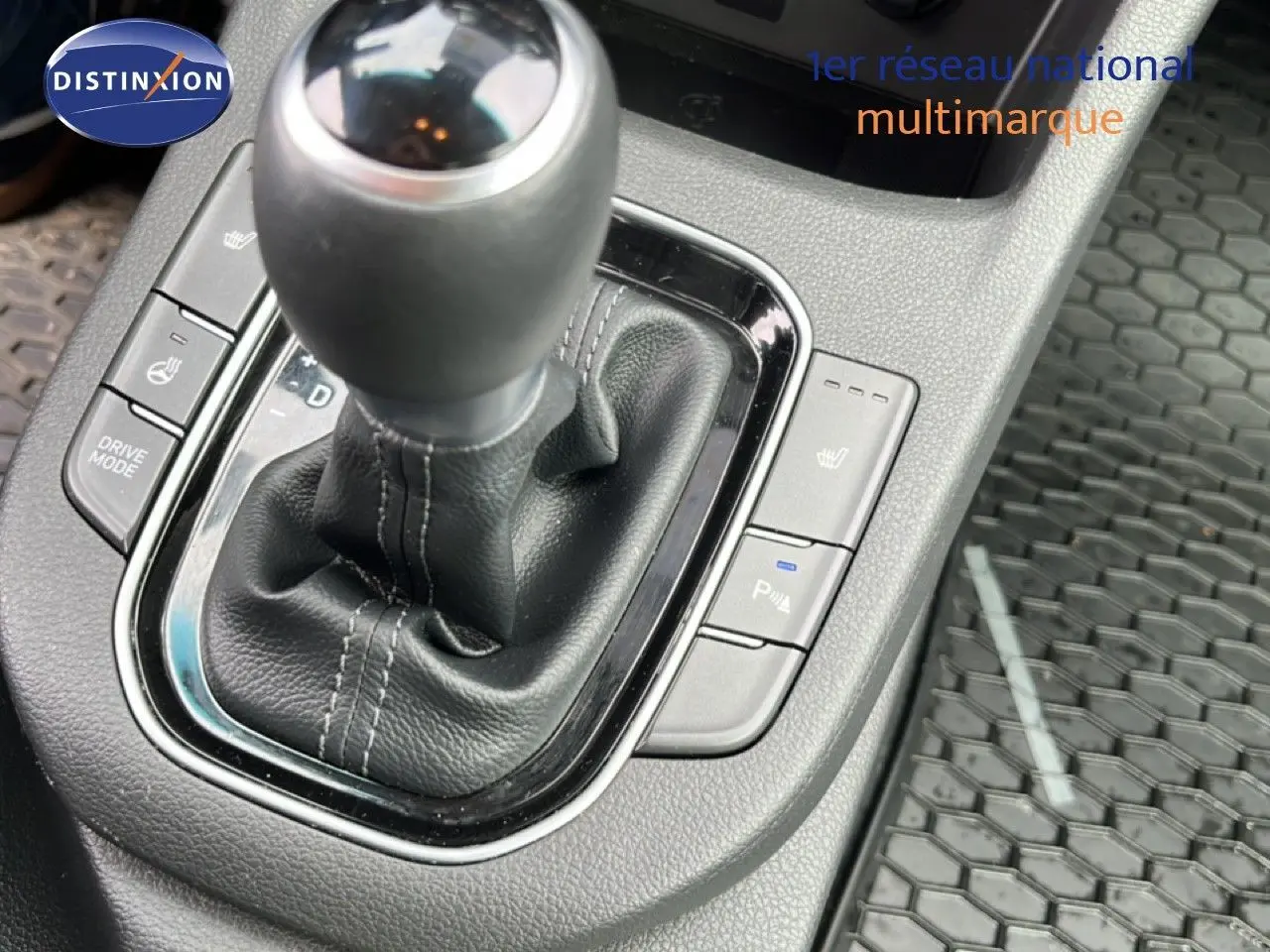 Gros plan sur le levier de vitesses en cuir noir de la Hyundai i30 SW 2023, avec boutons de siège chauffant et mode conduite.