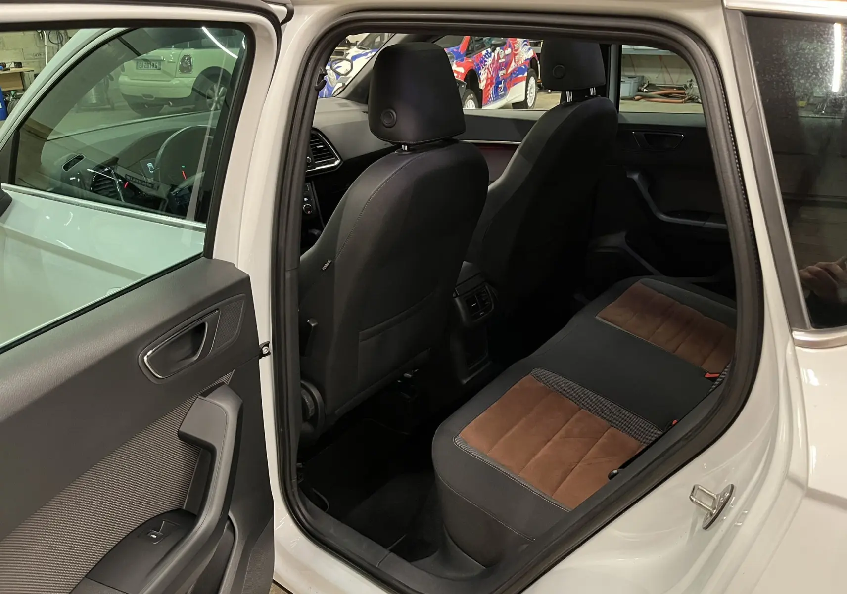 Vue intérieure côté arrière droit du SEAT Ateca blanc 2016, montrant les sièges arrière bi-matière noir et marron.