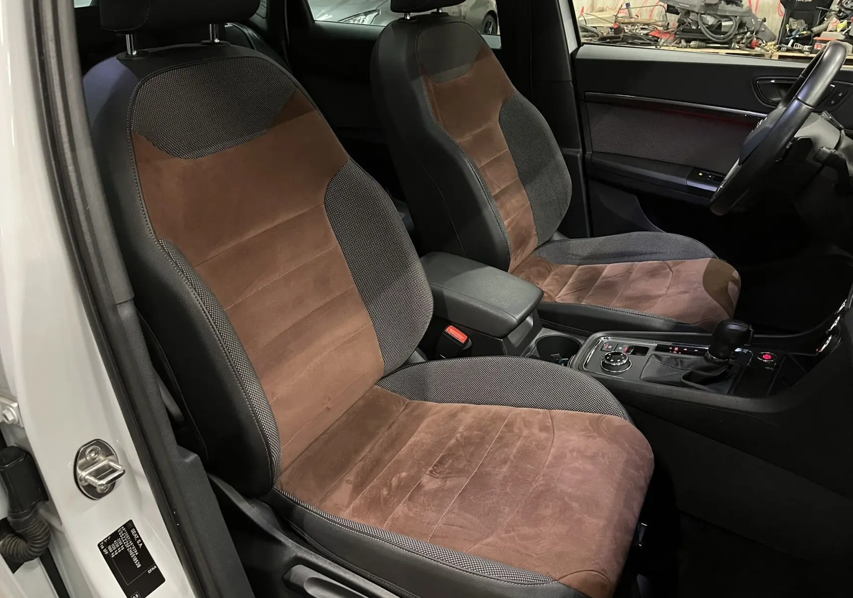 Vue intérieure côté conducteur du SEAT Ateca blanc, mettant en valeur les sièges marron et noirs en tissu et alcantara.