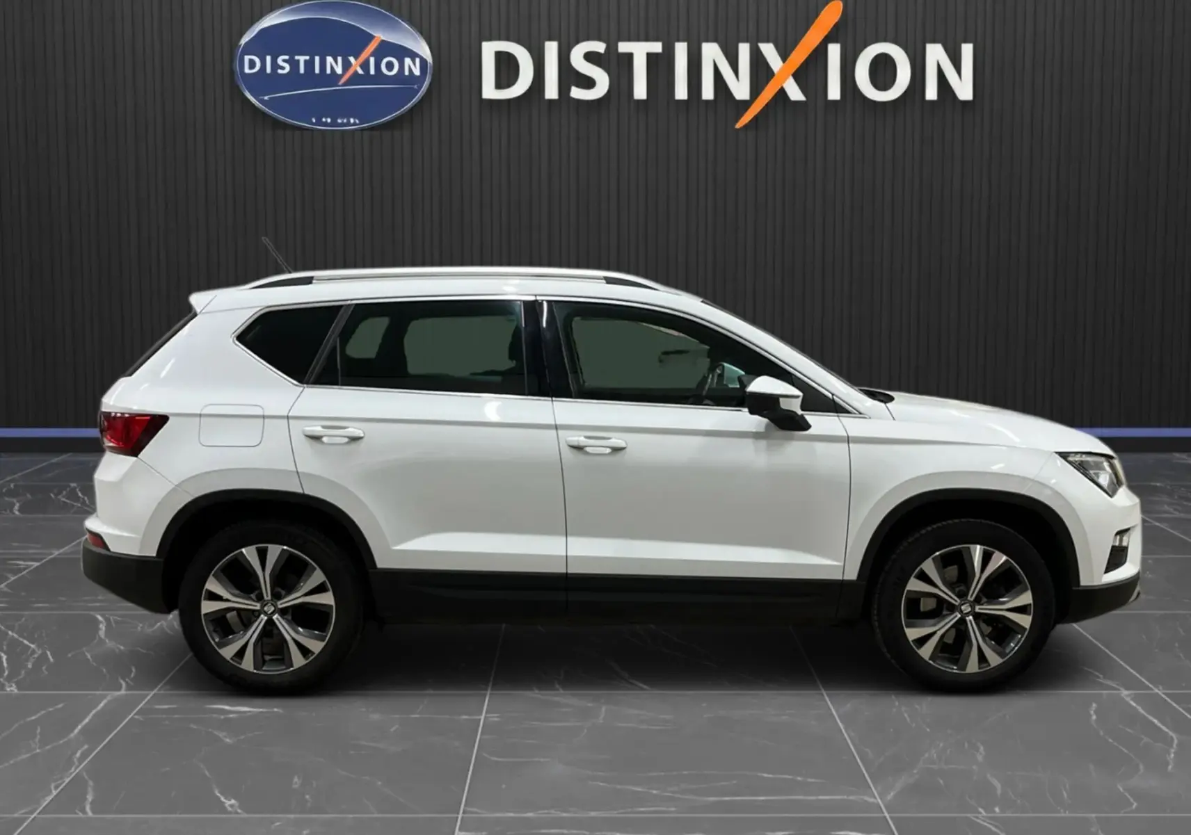 Vue de profil côté gauche d'un SEAT Ateca blanc 2016, avec jantes alliage bicolores et toit ouvrant.