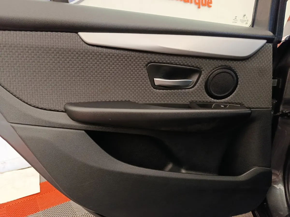 Vue rapprochée de la porte arrière droite intérieure grise de la BMW Série 2 Gran Tourer F46 avec poignée alu et haut-parleur rond.