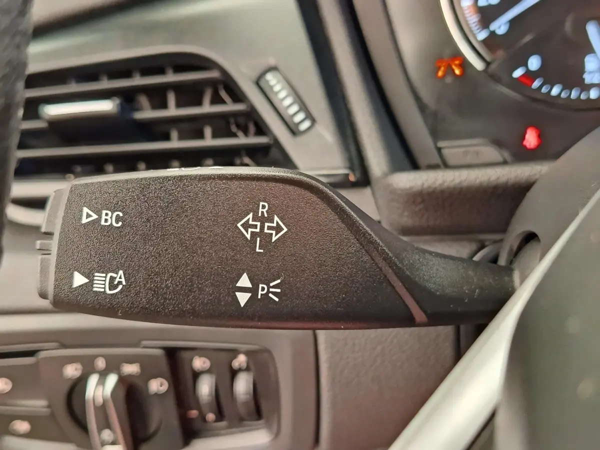 Gros plan sur la manette de clignotants noire du tableau de bord d’une BMW Série 2 Gran Tourer gris clair.
