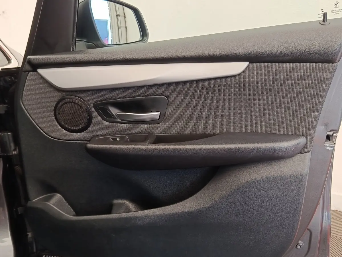 Vue rapprochée de la porte avant gauche de la BMW Série 2 Gran Tourer gris clair, avec garniture tissu et poignée alu.