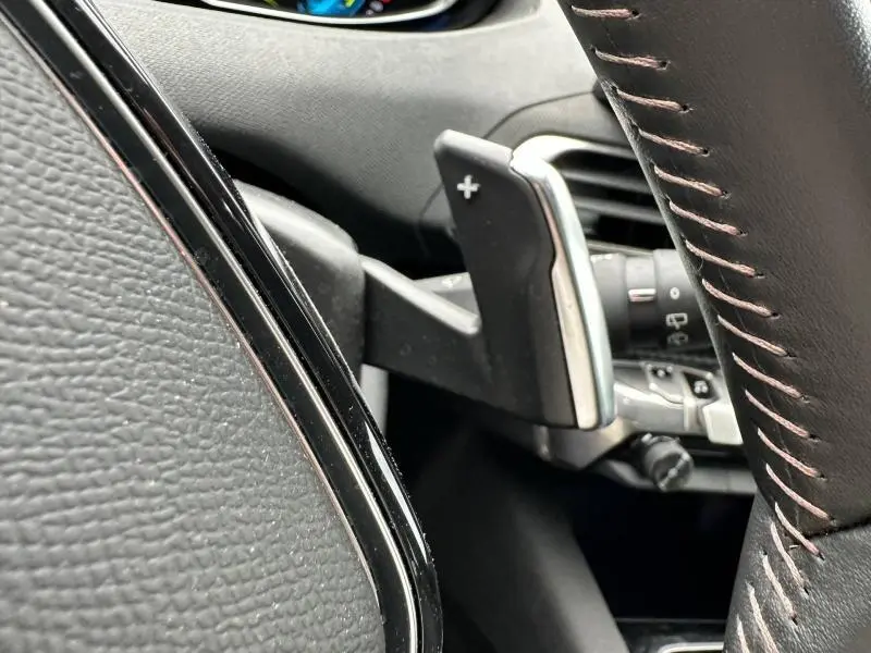 Gros plan sur la palette de changement de vitesse droite et le volant cuir noir du Peugeot 3008 Hybride Rechargeable 2024.