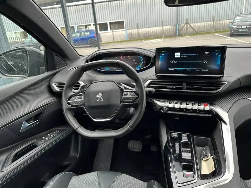Vue intérieure du poste de conduite du Peugeot 3008 Hybride Rechargeable noir Perla Nera, avec volant multifonction et écran tactile central.