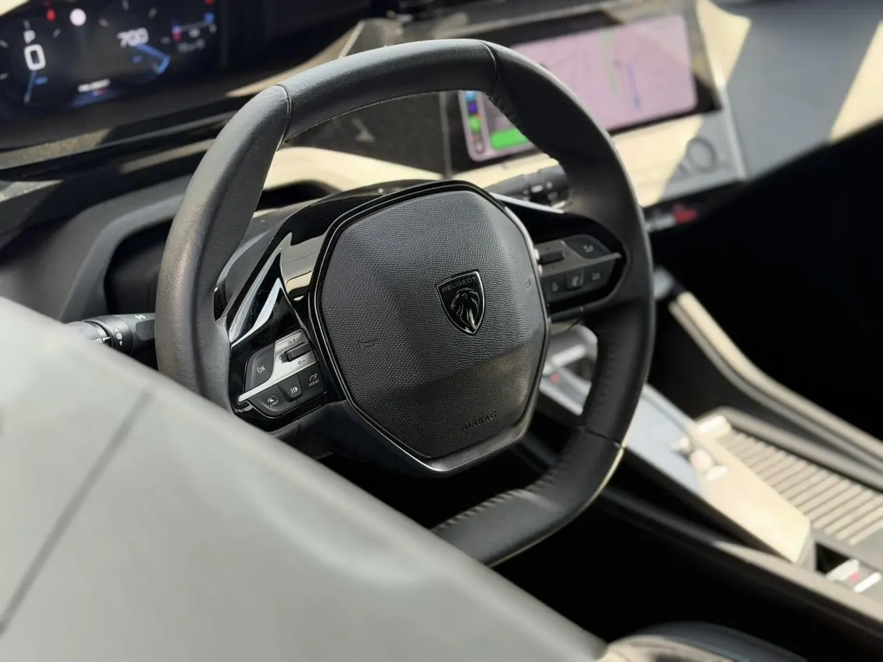 Vue rapprochée du volant cuir noir de la Peugeot 308 SW 2025 avec tableau de bord numérique et écran tactile central.
