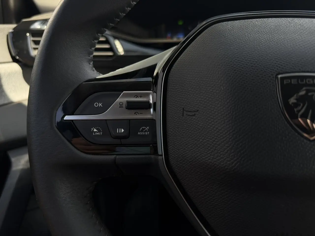 Gros plan sur la partie gauche du volant noir de la Peugeot 308 SW 2025 avec commandes du régulateur adaptatif.