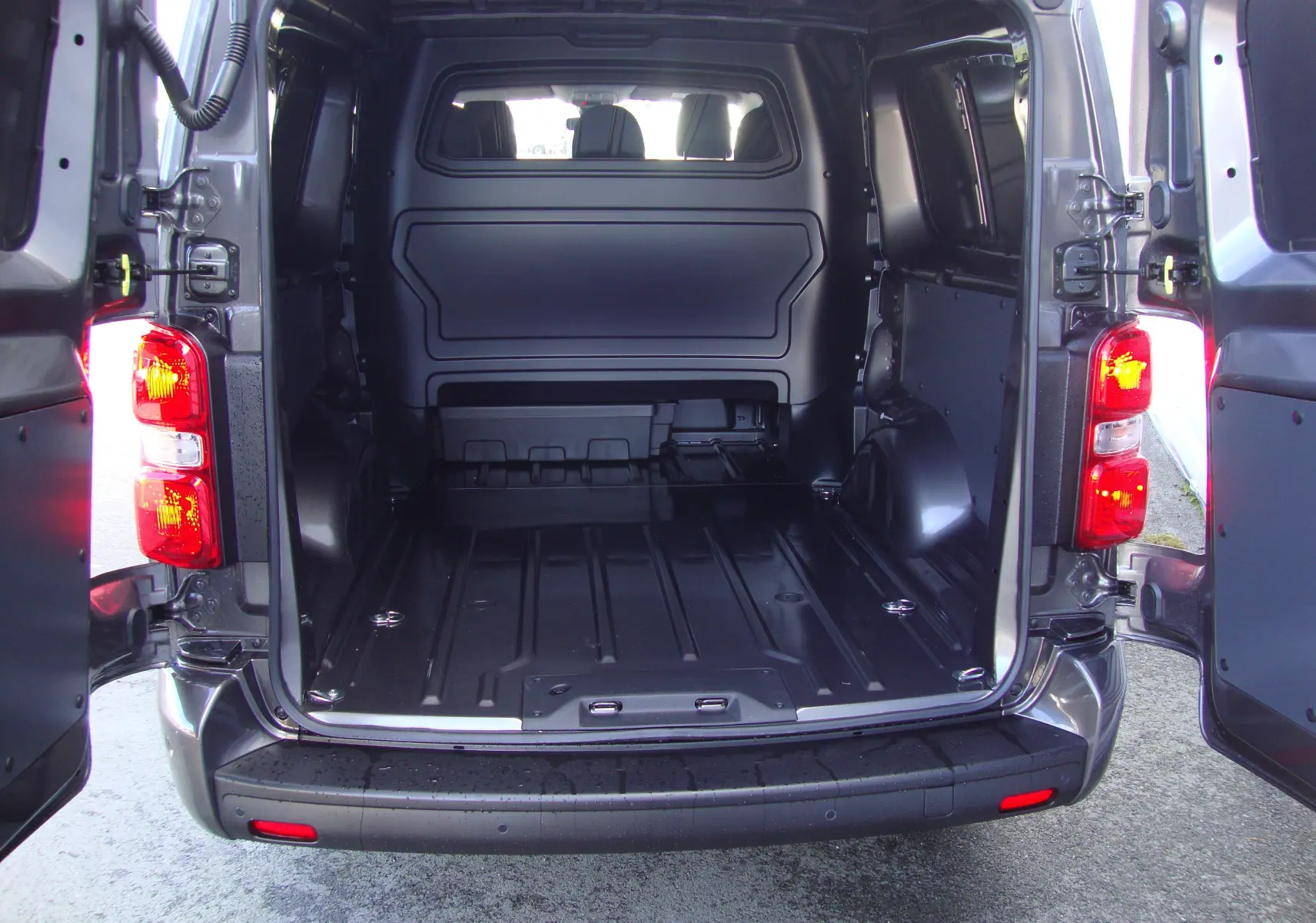 Vue arrière ouverte du Citroën Jumpy XL gris platinum montrant l'espace de chargement vide et la cabine approfondie.