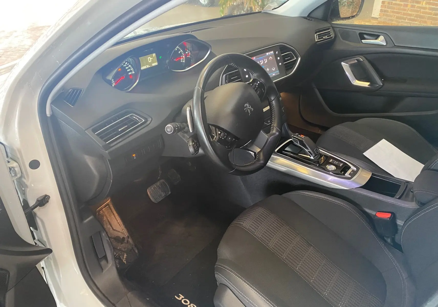 Intérieur noir de la Peugeot 308 blanc vue côté conducteur, tableau de bord et console centrale avec boîte auto visible.
