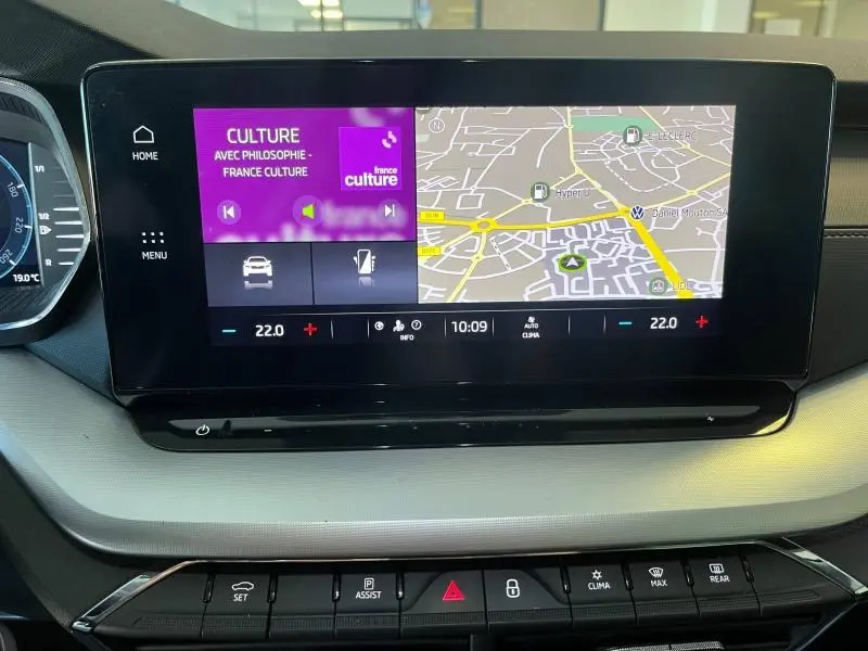 Écran tactile central de la Skoda Octavia Combi blanc, affichant navigation et radio France Culture en intérieur voiture.