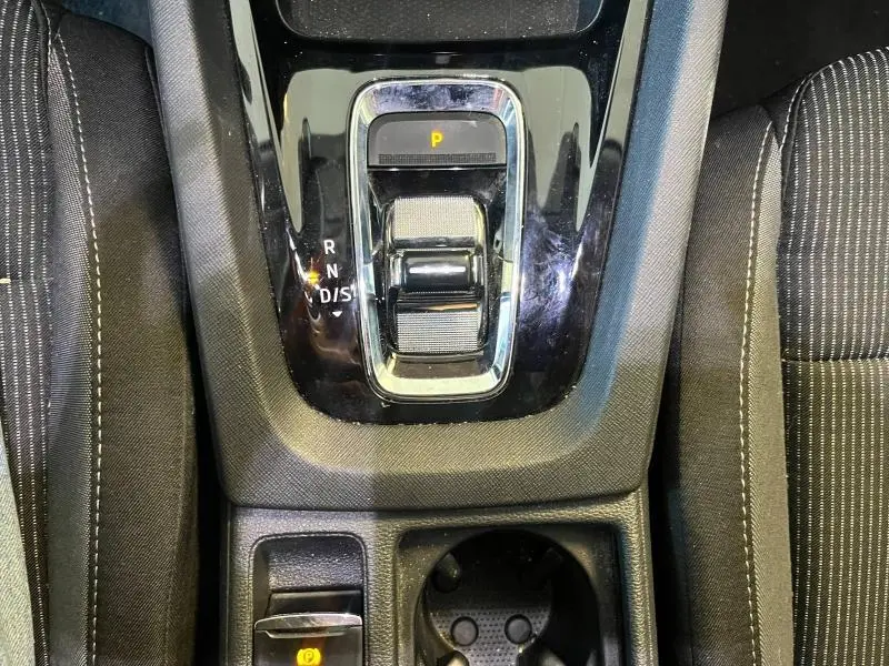 Vue plongeante sur la console centrale noire avec levier de vitesses automatique et sièges tissu noir à surpiqûres blanches.