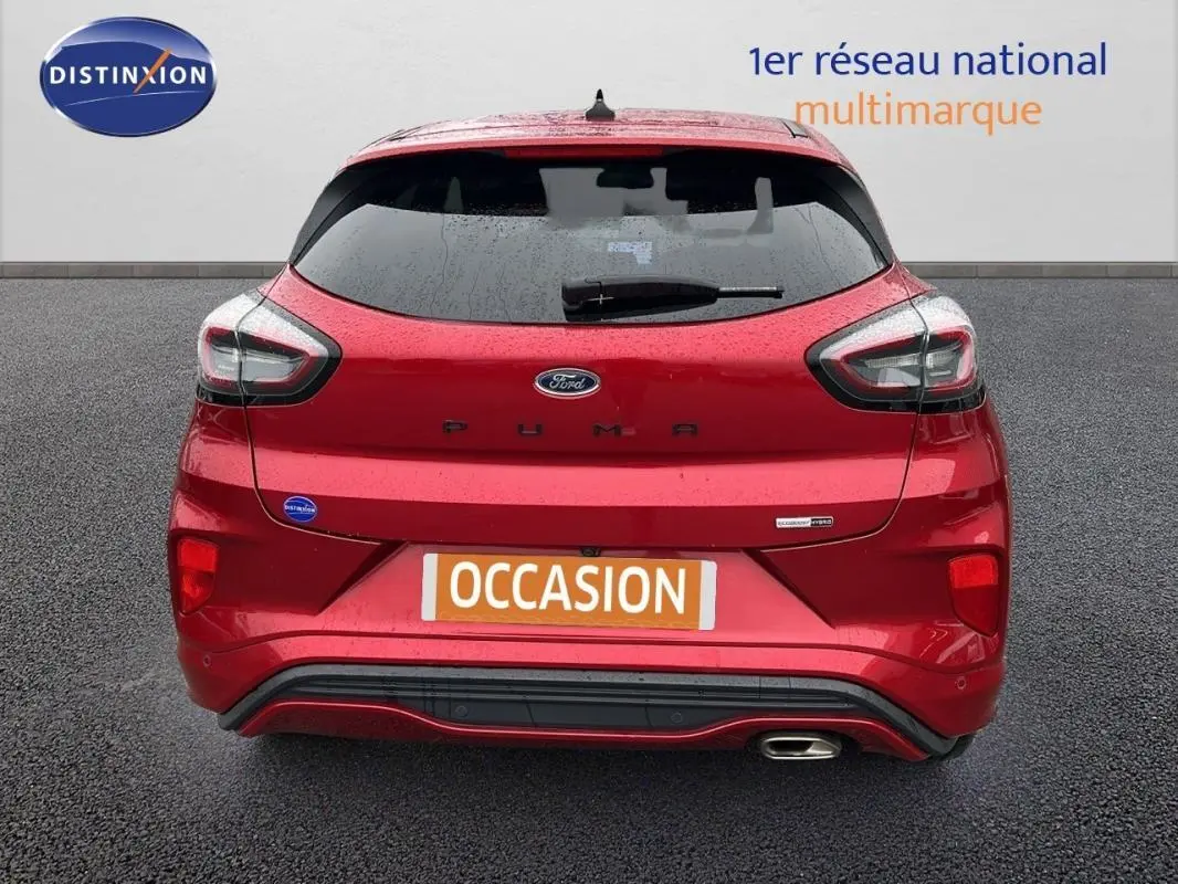 Vue arrière d'une Ford Puma rouge 2020 avec feux LED et sortie d'échappement chromée visible sur fond gris.