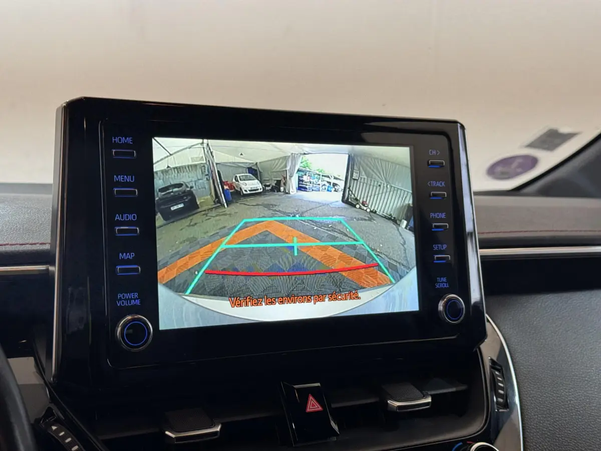 Écran tactile central affichant la caméra de recul dans l’habitacle d’une Toyota Corolla Hybride gris clair, vue intérieure frontale.