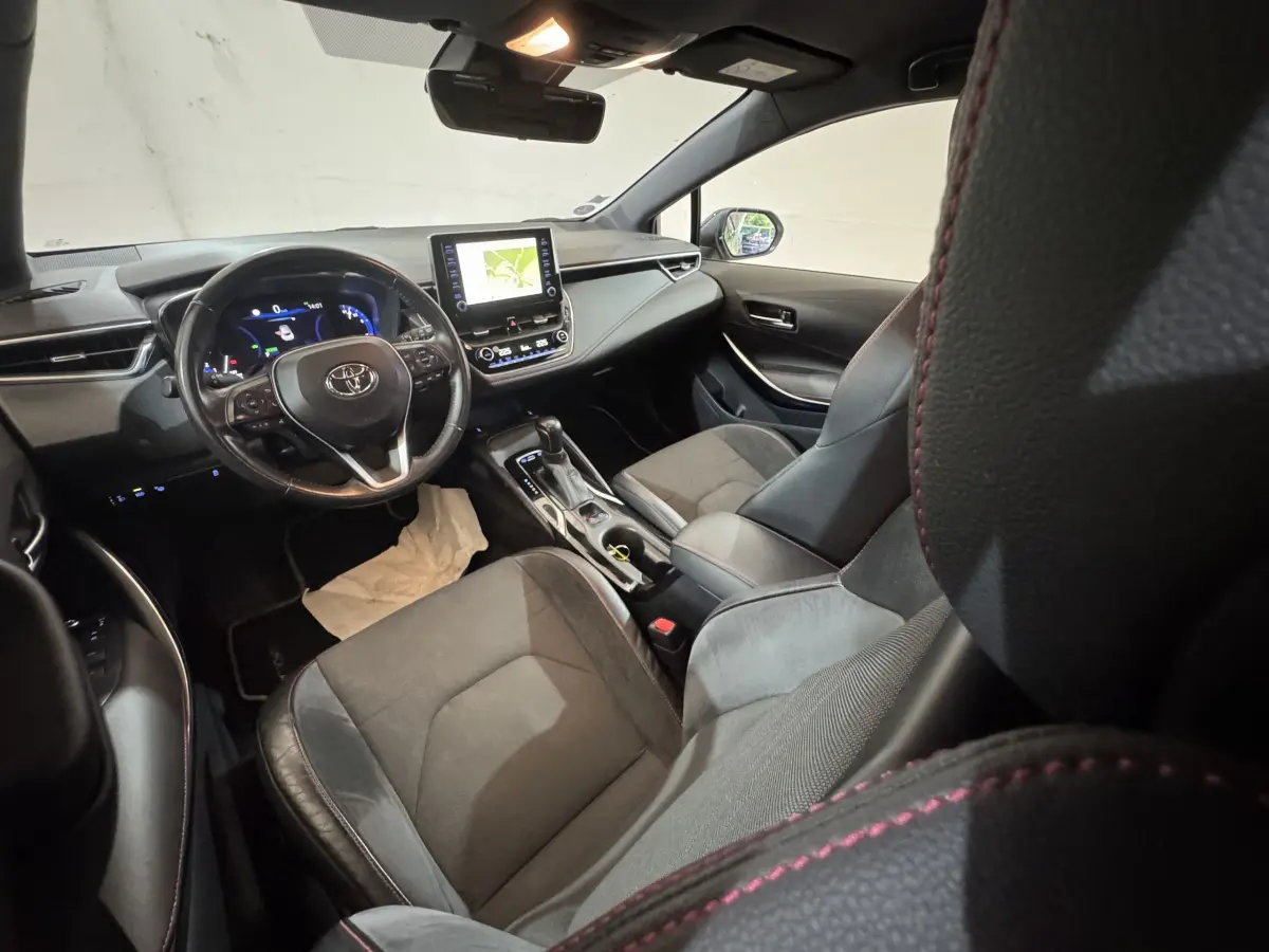 Intérieur de la Toyota Corolla Hybride 122h Collection vu côté conducteur, tableau de bord noir avec écran tactile et volant cuir.