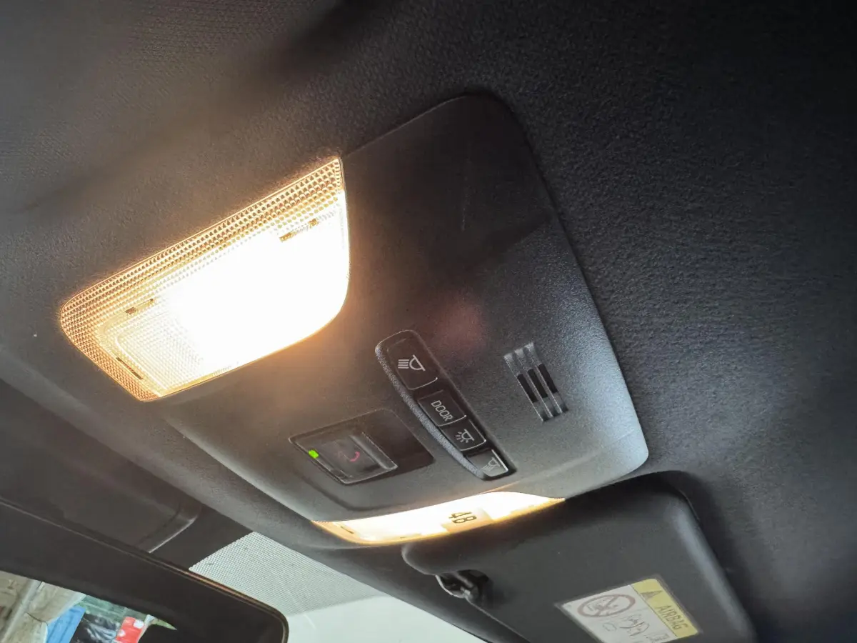 Plafonnier intérieur allumé avec commandes d’éclairage et micro, vue en contre-plongée dans une Toyota Corolla gris clair hybride 2021.