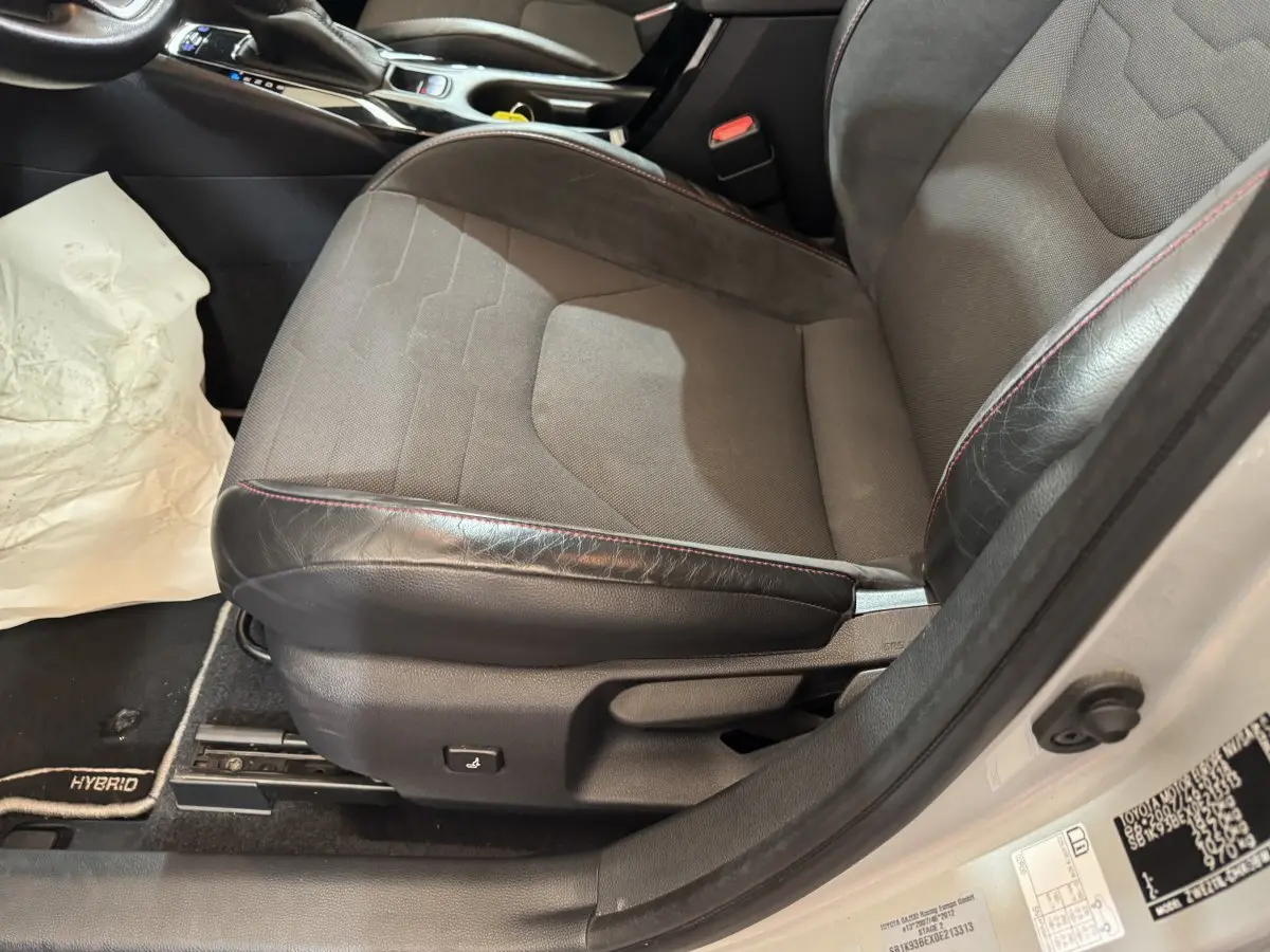 Gros plan sur le siège avant droit gris et noir avec surpiqûres rouges de la Toyota Corolla Hybride 122h Collection 2021.