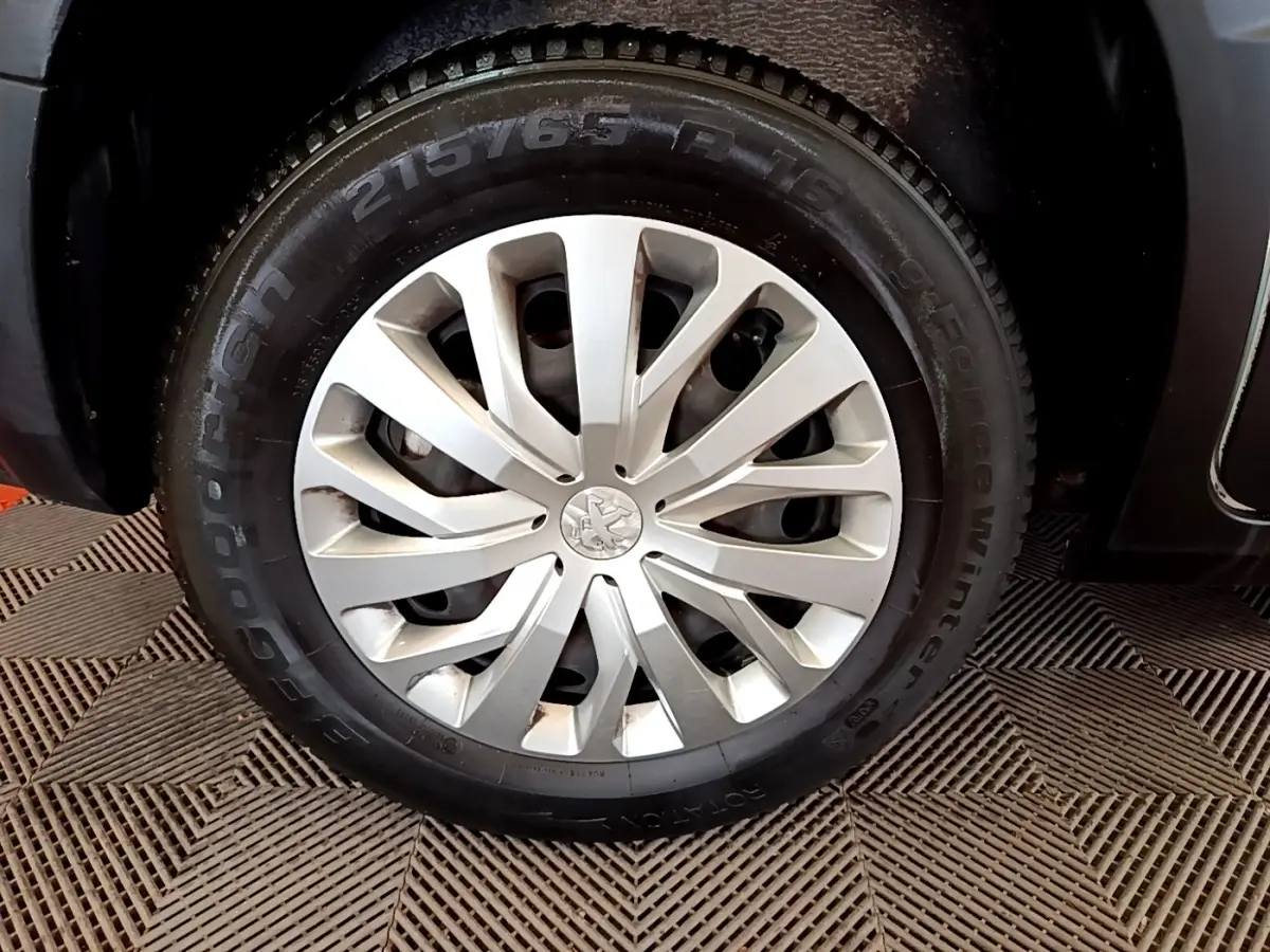 Gros plan sur la roue avant droite du Peugeot Rifter blanc, mettant en valeur la jante argentée et le pneu hiver Goodyear.