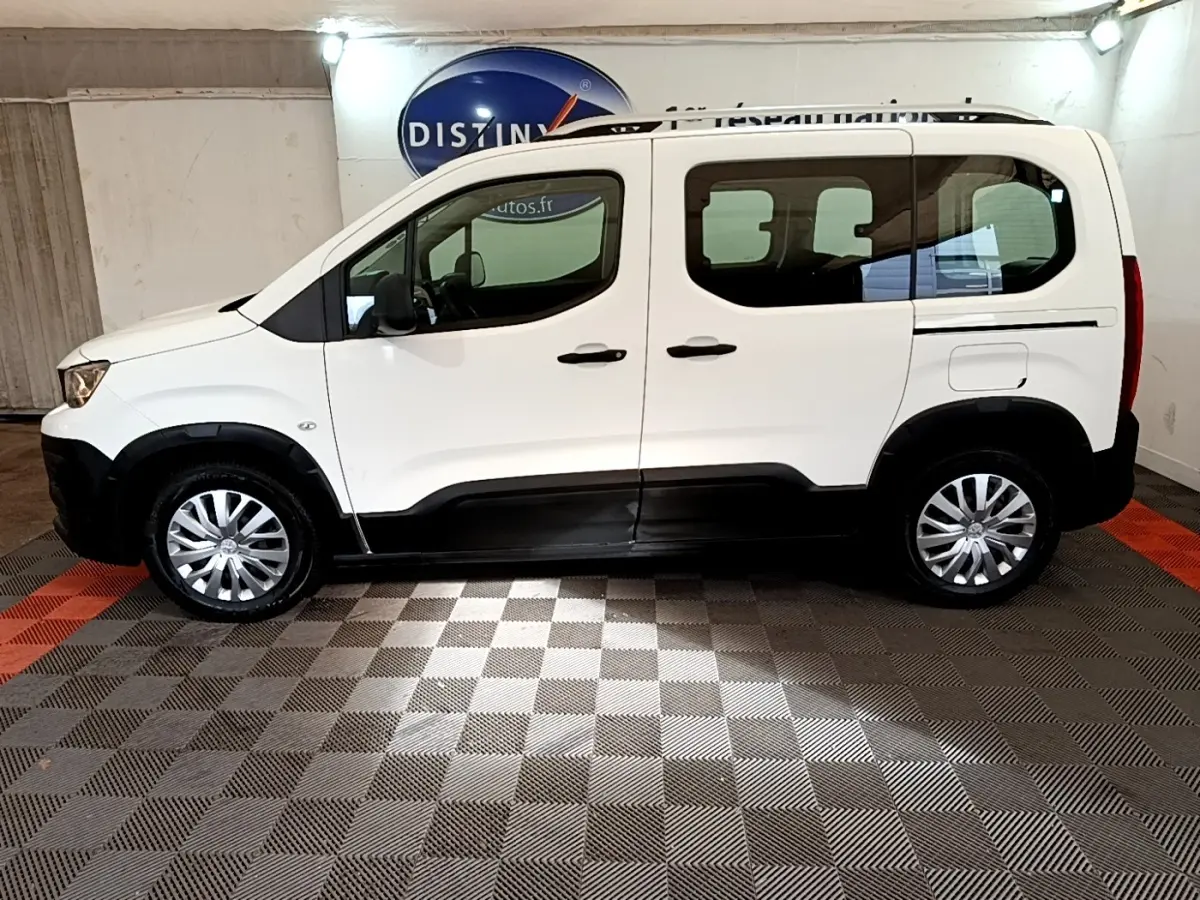 Peugeot Rifter blanc vue de profil côté gauche, avec protections noires sur bas de caisse et roues argentées.