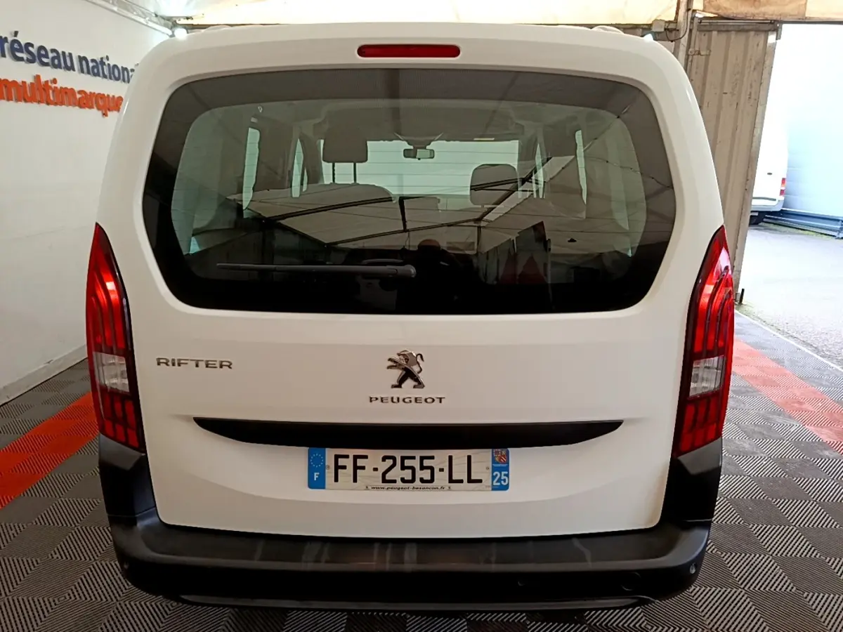 Vue arrière du Peugeot Rifter blanc de 2019 avec hayon vitré et feux arrière verticaux rouges.
